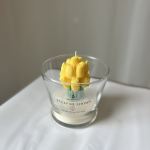 Yellow tulip-shaped candle in a clear glass container