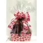 Gift basket wrapped in clear cellophane with a large heart-patterned bow