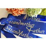 Blue satin ribbons with gold lettering beside peach and white flowers