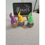 Three colorful gnome figurines displayed in front of a flower market sign