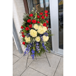Standing floral spray with red roses, cream blooms, and blue orchids