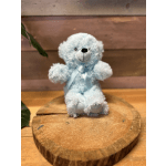 Light blue teddy bear with a ribbon sitting on a wooden slice