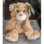 Plush teddy bear sitting on a wooden surface with a hang tag