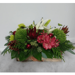 Low floral arrangement with white lilies, pink blooms, and green accents in a wooden box