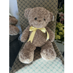 Plush teddy bear with a yellow ribbon sitting on a patterned chair
