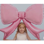Young girl holding a large pink bow-shaped balloon