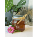 Jar of honey wrapped in plastic with a pink flower beside it