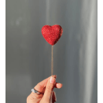 Hand holding a glittery red heart pick on a thin stem