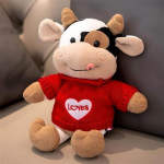 Plush cow toy wearing a red sweater with a heart graphic