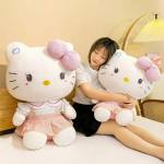 Woman sitting with two large Hello Kitty plush toys on a bed