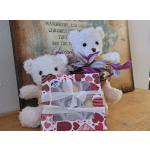 Two white teddy bears with a heart-pattern gift box and purple potted flowers