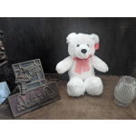 White teddy bear with a pink ribbon beside a decorative floral shop sign