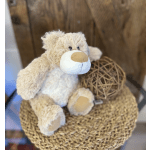 Beige plush teddy bear sitting beside a wicker sphere on a woven mat