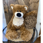 Brown plush teddy bear sitting beside a decorative twig ball on a glass table