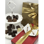 Tiered tray of assorted chocolates beside ribbon-wrapped gift boxes