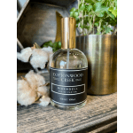 Perfume bottle beside cotton bolls and a potted plant
