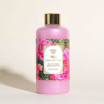 Pink bubble bath bottle with floral label and gold cap on a light background