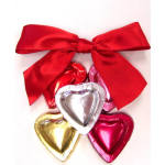 Heart-shaped foil-wrapped chocolates in assorted colors with a large red satin bow on top