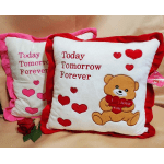 Two heart-themed decorative pillows with a teddy bear and rose