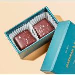 Two chocolate squares in a blue gift box with a lid beside it