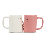 Two ceramic mugs touching face-to-face, one white and one pink