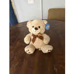 Beige teddy bear with a brown ribbon sitting on a table
