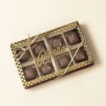 Box of milk chocolates in a gold checkered package with clear lid and ribbon