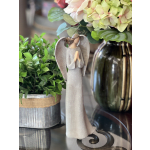 Angel figurine beside a potted plant and a vase of pale flowers