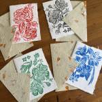 Floral print cards and folded handmade paper on a wooden surface