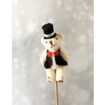 Small plush teddy bear in a tuxedo on a wooden stick against a soft gray background