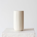 Cream ribbed ceramic vase on a white block