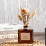 Dried floral arrangement in an amber square bottle vase