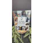 A book titled At Home with Dogs stands on a wooden slice with faux greenery.