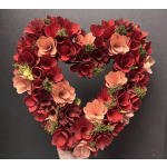Heart-shaped arrangement of red and peach flowers on a dark background