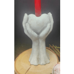 White hands holding a heart-shaped candle holder with a red candle
