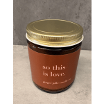 Amber glass jar candle with gold lid and brown label reading 'so this is love.'