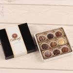 Box of assorted chocolate truffles beside its lid