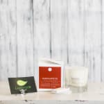 Two candles with a matchbox and a small card on a table