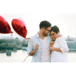 Couple embracing with red heart-shaped balloons outdoors