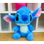 Blue plush toy with large ears and a white belly sitting on a wooden surface