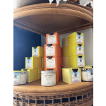 Stacked scented candles in colorful boxes on a wicker shelf