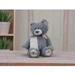 Gray plush teddy bear with a ribbon and tag sitting on a wooden table