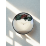 Round white candle in a metal tin with dried petals on top