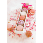Box of decorated macarons with pink ribbon and scattered sprinkles