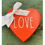 Red heart-shaped box with the word LOVE and a white ribbon