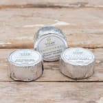 Three foil-wrapped aromatherapy shower steamers on a wooden surface