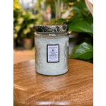 A scented candle in a glass jar with a patterned lid