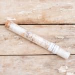 A single wrapped floral stem in a clear tube on a wooden surface