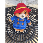 Plush teddy bear wearing a red hat and blue coat
