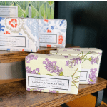 Wrapped bars of handmade soap with floral labels on wooden shelves